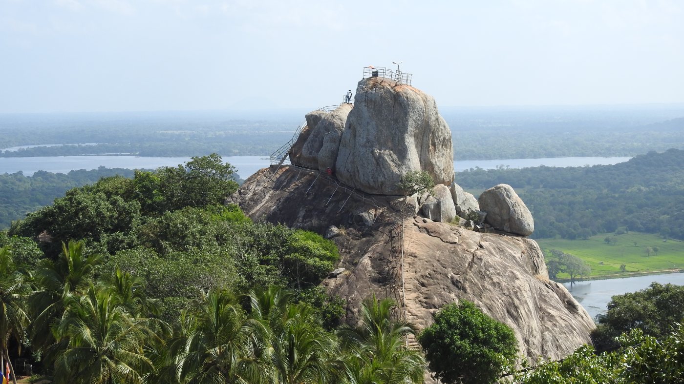 Aradhana Gala rock at Mihintale, with railings on the summit and lakes and forest beyond