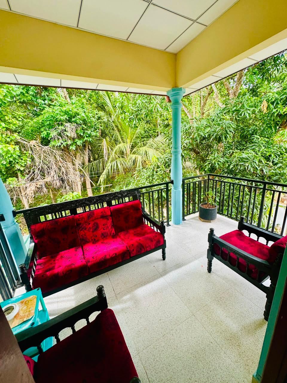 Balcony sofa with red cushions surrounded by green trees