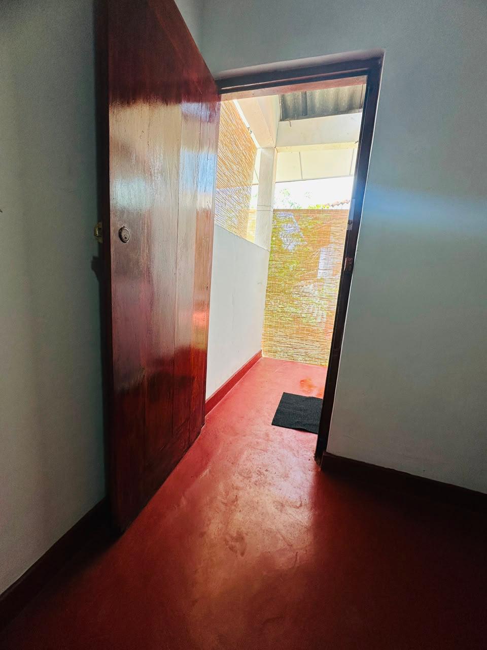 Polished wooden door opening from a room onto a shaded veranda