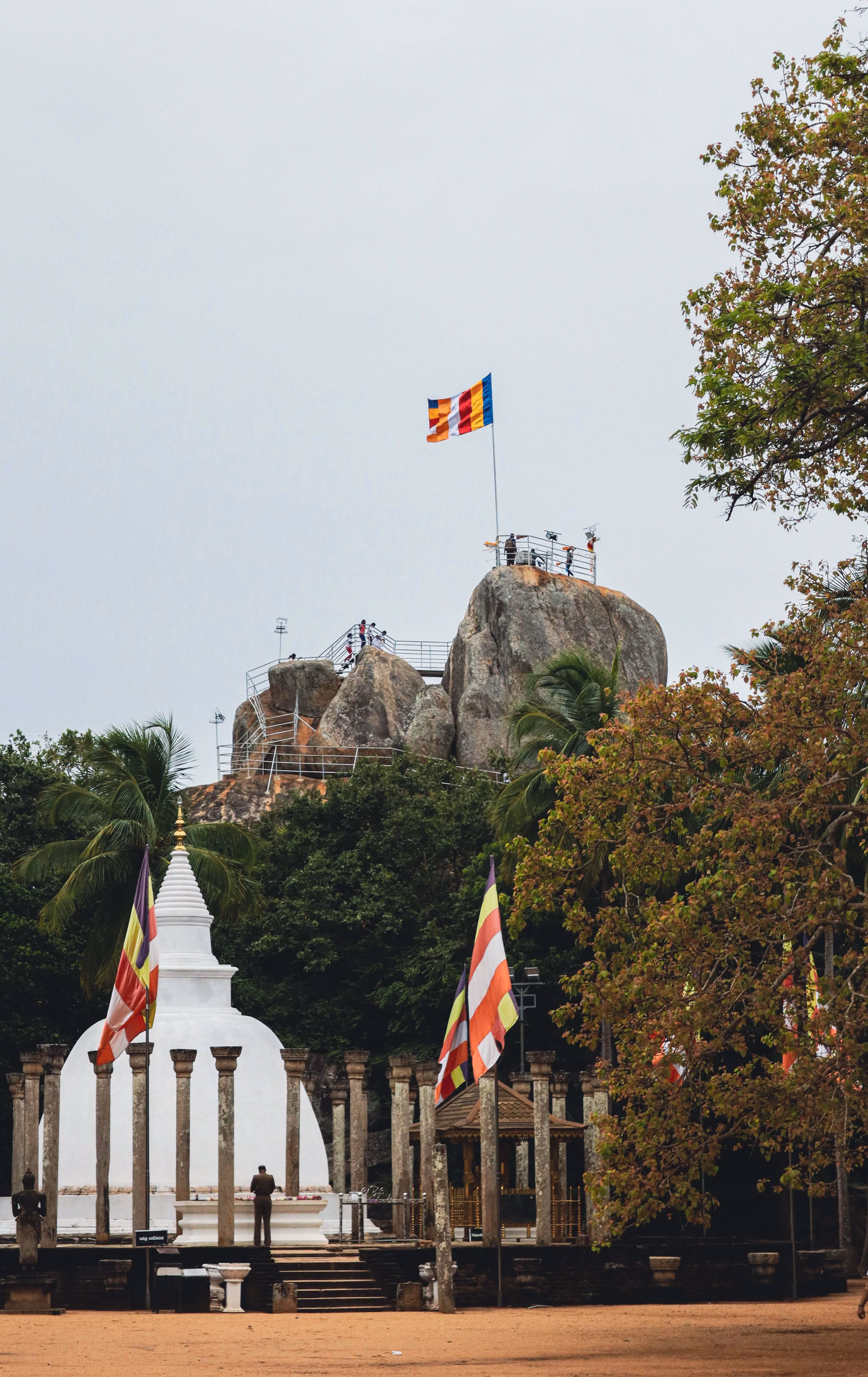Aradhana Gala rock at Mihintale with a white stupa and Buddhist flags in the foreground