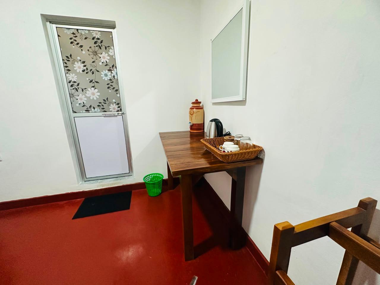 Wooden table with an electric kettle, cups, glasses and a tea tray in a guest room