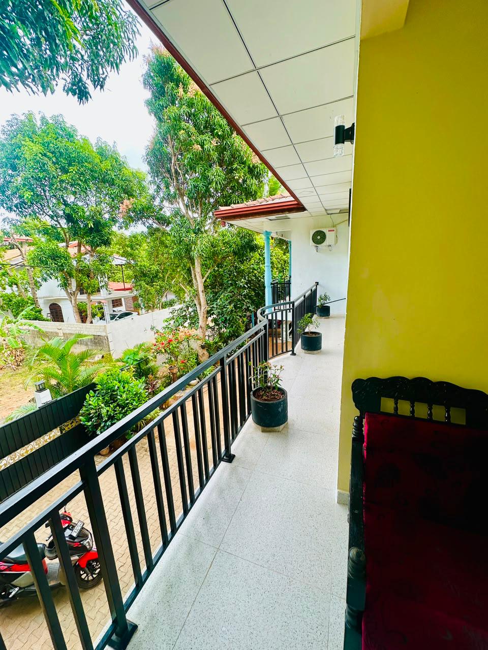 Upstairs veranda at Silva Homestay overlooking the garden, with a rental scooter parked in the courtyard below
